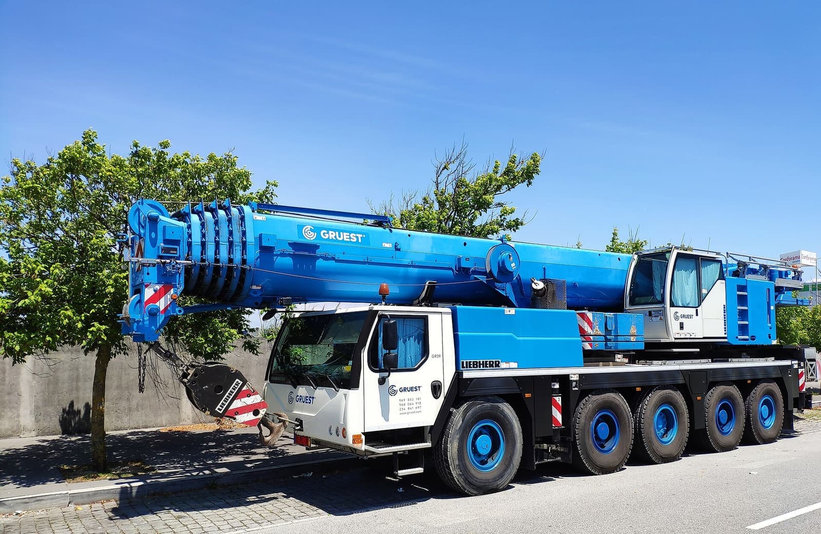Mobile crane biru beroda banyak terparkir di tepi jalan